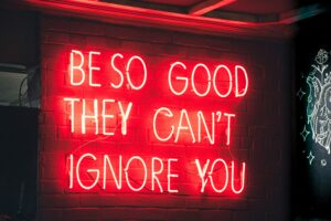 Red glowing sign that says 'be so good they can't ignore you.'