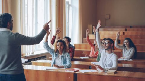 students raising hands in class